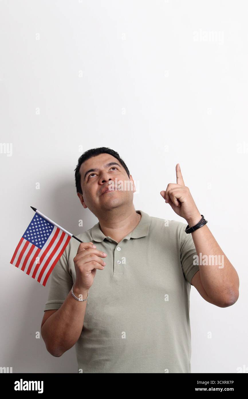 L'homme adulte latino à la peau foncée arbore le drapeau des États-Unis, sa nouvelle nationalité en tant que migrant Banque D'Images L'homme adulte latino à la peau foncée arbore le drapeau des États-Unis, sa nouvelle nationalité en tant que migrant Banque D'Images