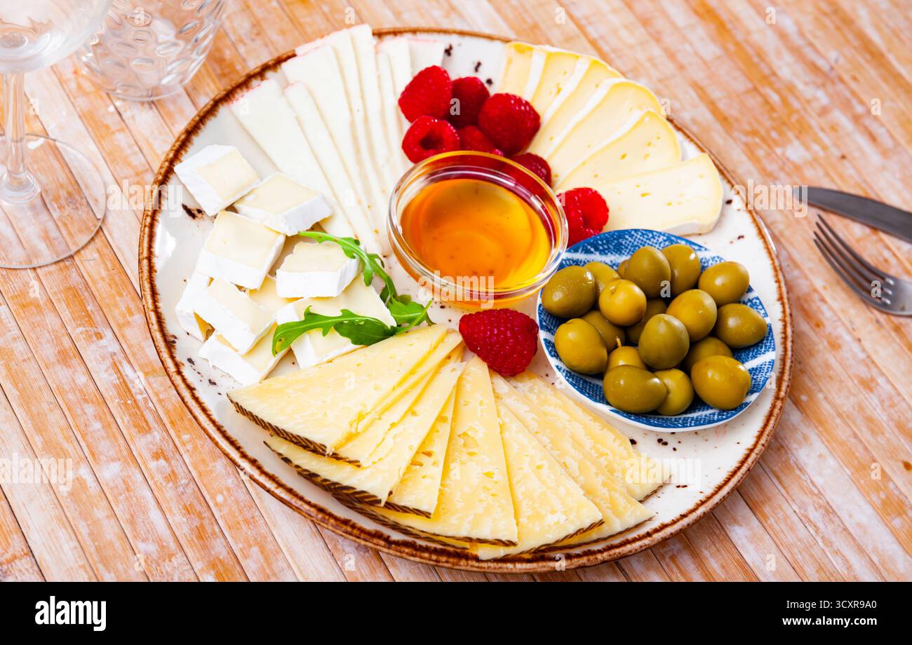 Assiette avec différents types de fromage, framboises et olives Banque D'Images