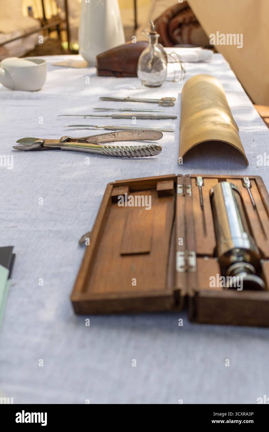 Un kit chirurgical vintage avec des instruments et un parchemin roulé sur une nappe de lin dans une lumière douce Banque D'Images