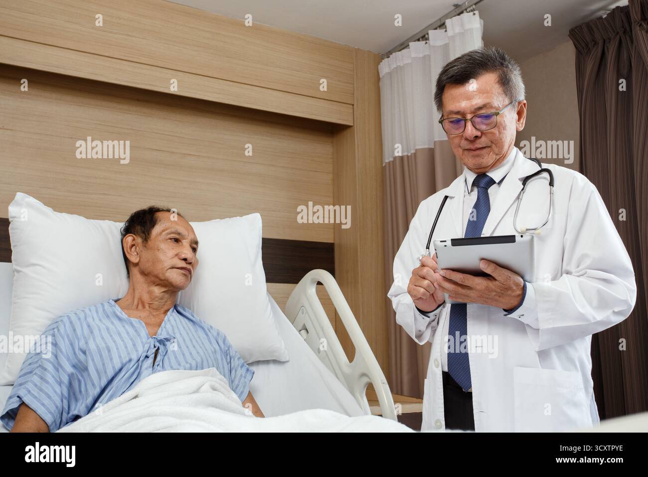 Patient cancéreux âgé allongé sur le lit d'hôpital parlant avec le médecin tenant un comprimé. consultation médicale et bilan médical en chambre d'hôpital, pro Banque D'Images Patient cancéreux âgé allongé sur le lit d'hôpital parlant avec le médecin tenant un comprimé. consultation médicale et bilan médical en chambre d'hôpital, pro Banque D'Images