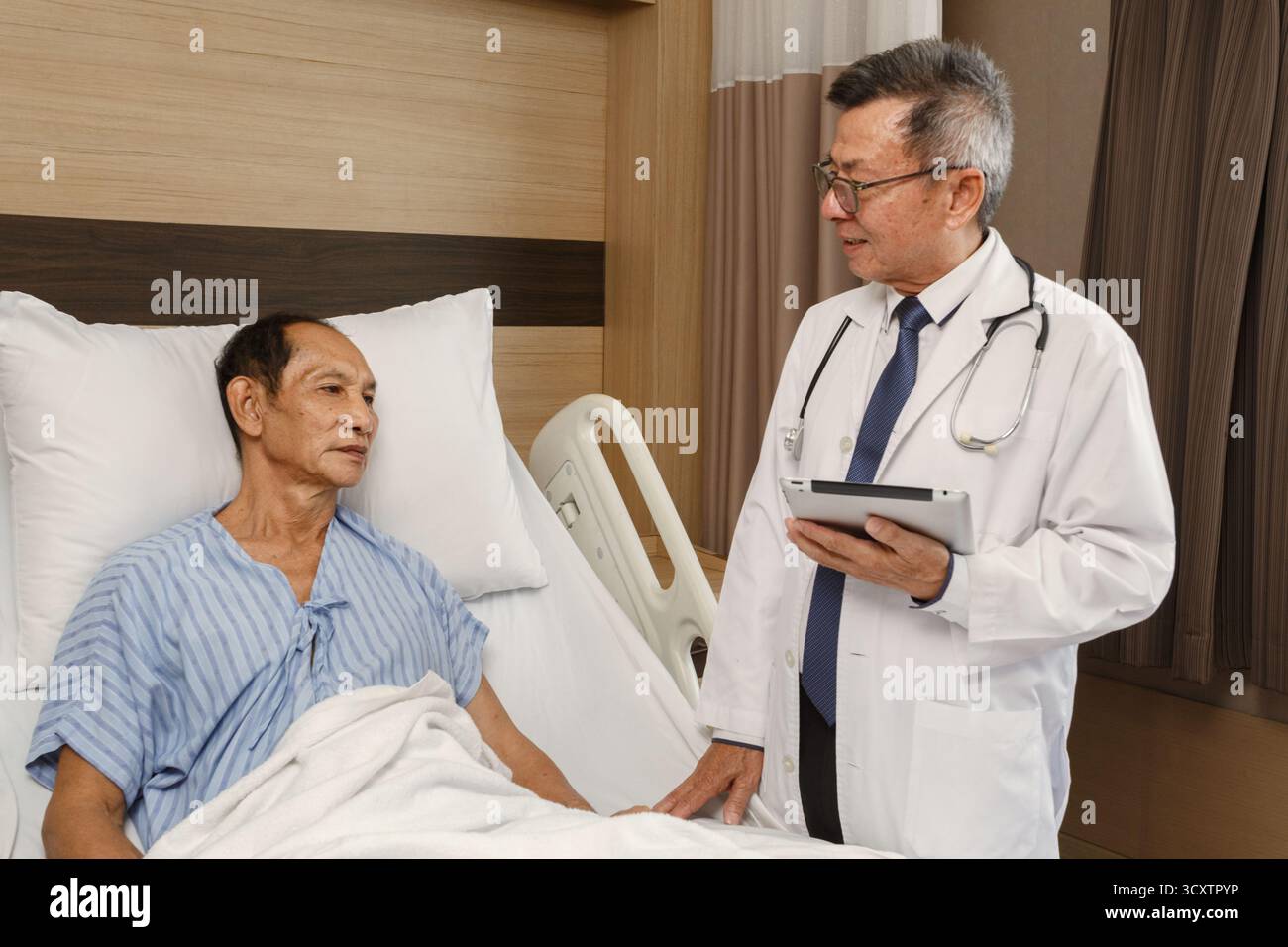 Patient cancéreux âgé allongé sur le lit d'hôpital parlant avec le médecin tenant un comprimé. consultation médicale et bilan médical en chambre d'hôpital, pro Banque D'Images Patient cancéreux âgé allongé sur le lit d'hôpital parlant avec le médecin tenant un comprimé. consultation médicale et bilan médical en chambre d'hôpital, pro Banque D'Images