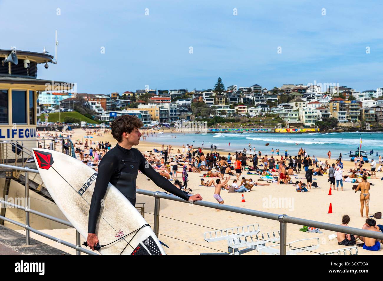 Surfeur regarde au-dessus d'une plage bondée de Bondi Beach, Sydney, Australie Banque D'Images