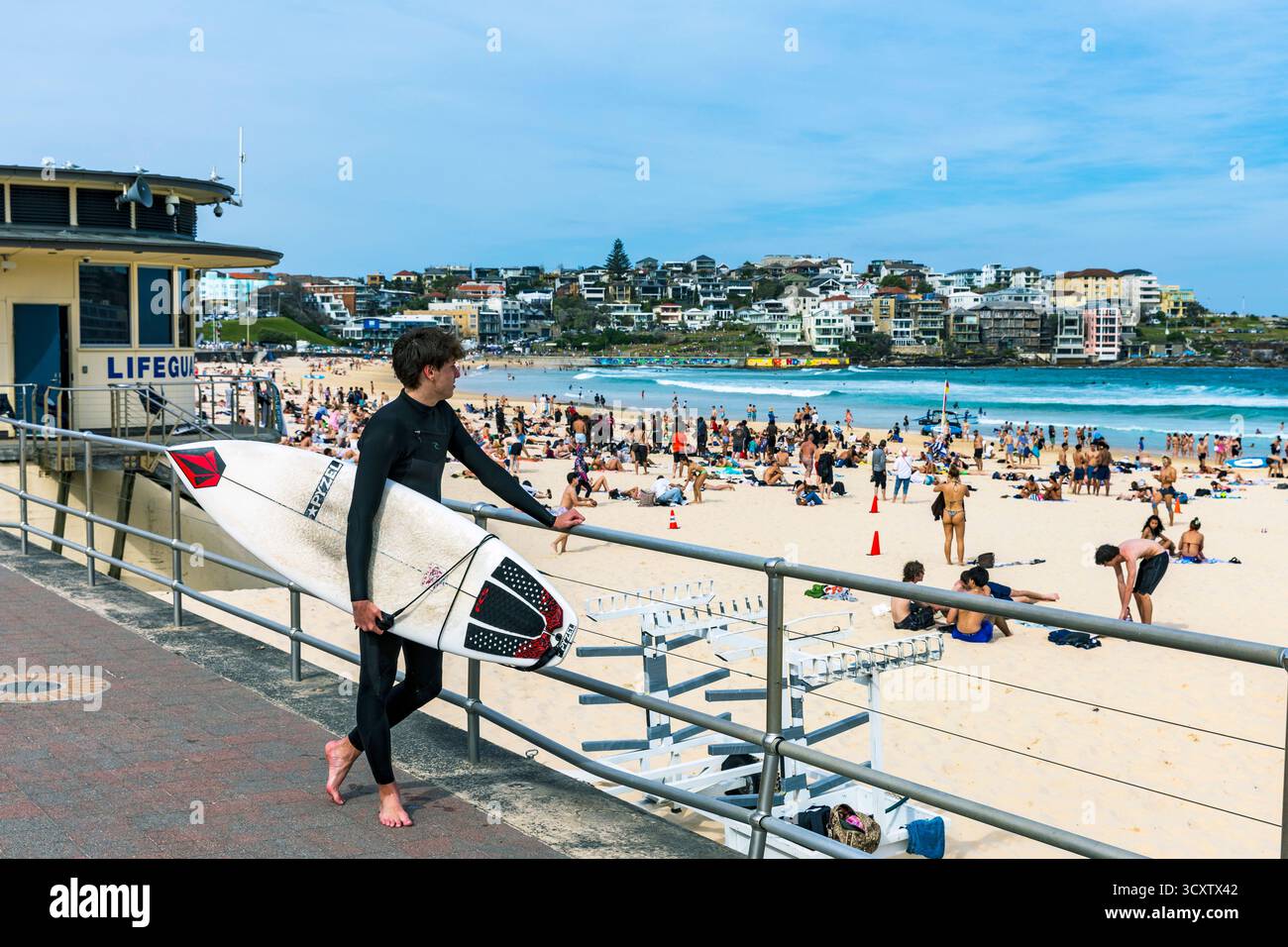 Surfeur regarde au-dessus d'une plage bondée de Bondi Beach, Sydney, Australie Banque D'Images
