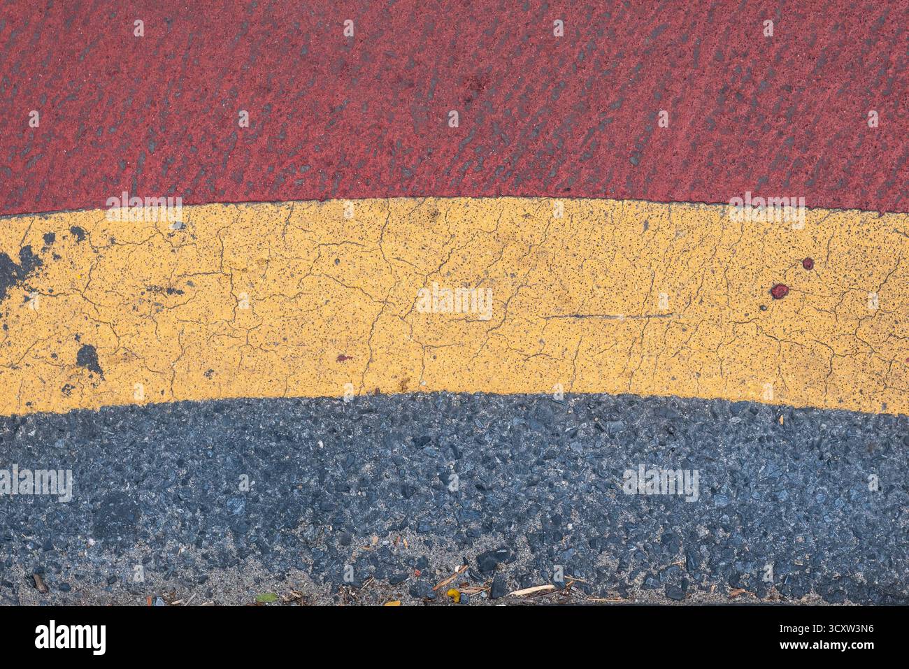 Texture de route goudronnée grise avec peinture rouge et jaune Banque D'Images