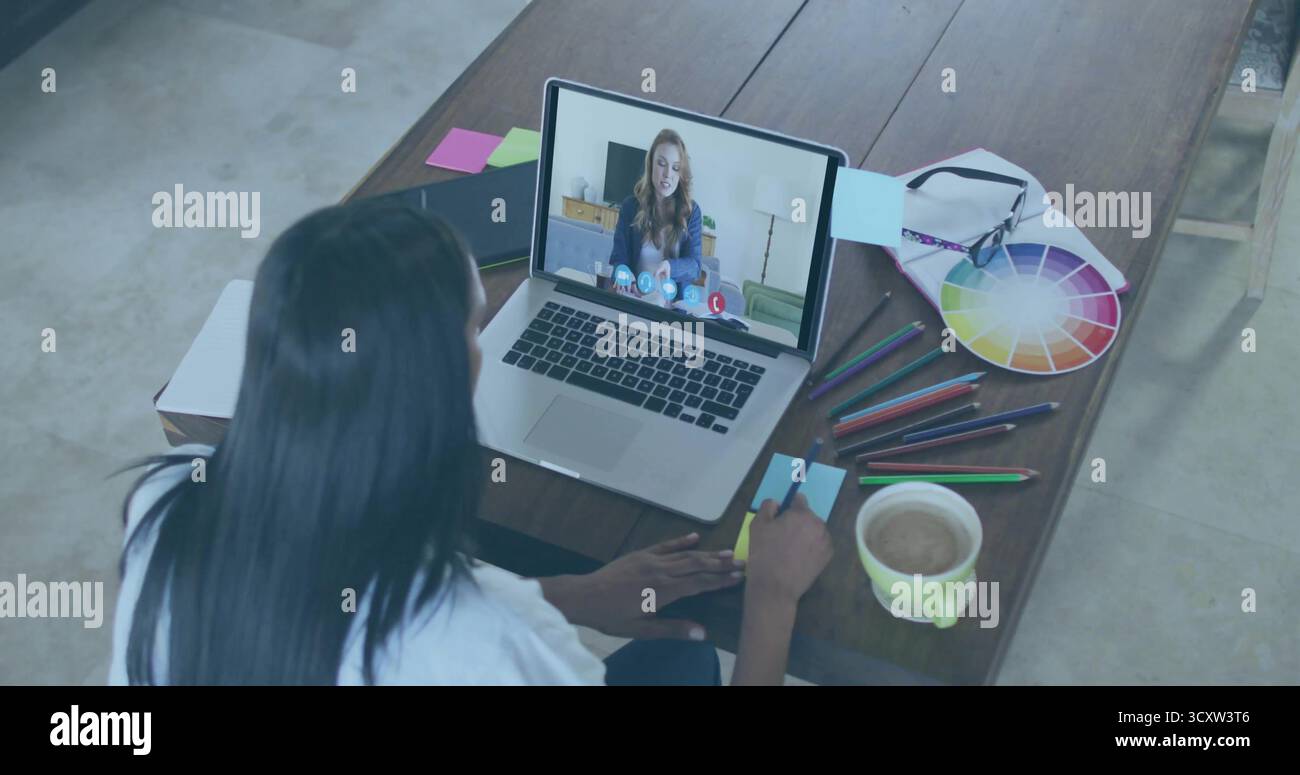 Femme écrivant portant une note collante blanche à la maison, avec ordinateur portable, roue de couleur et crayons Banque D'Images