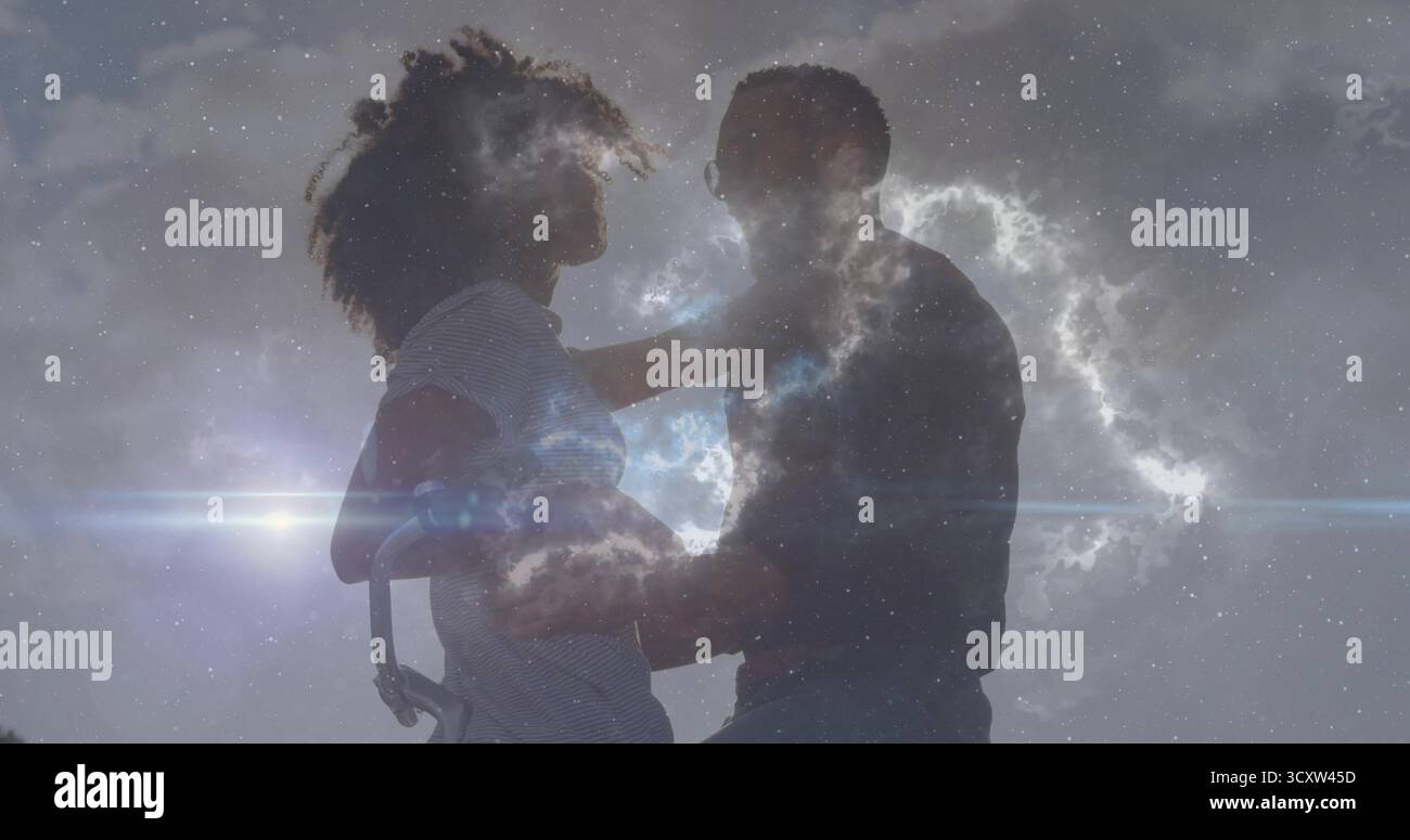 Couple embrassant debout dans un espace extérieur ouvert sous un ciel partiellement nuageux, avec lumière parasite, lueur cosmique Banque D'Images