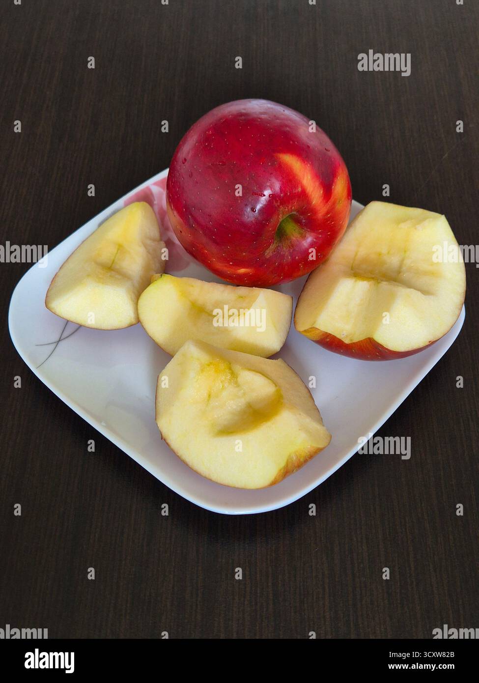 Une composition de ​​apples entiers et tranchés couchés sur une assiette est prête à manger comme collation saine et riche en vitamines. - Image de stock capturée avec un smartphone