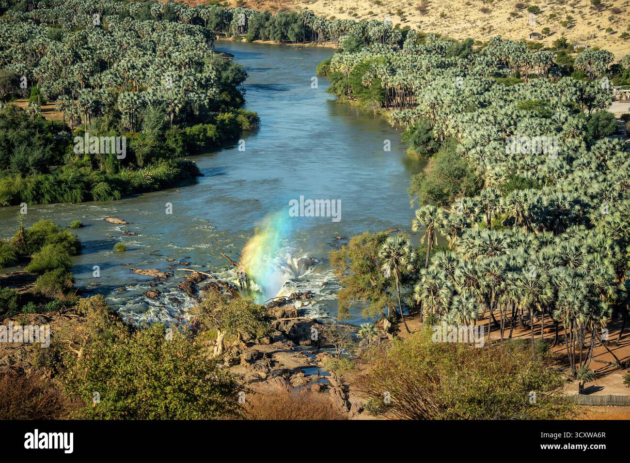 Un arc-en-ciel de lumière passant à travers le jet du canal principal des chutes d'Epupa depuis le point de vue Banque D'Images