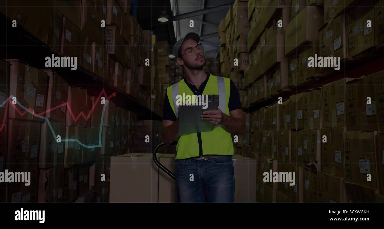 Vérification du stock, lecture des graphiques linéaires sur tablette dans l'allée à côté du transpalette par l'employé de l'entrepôt Banque D'Images