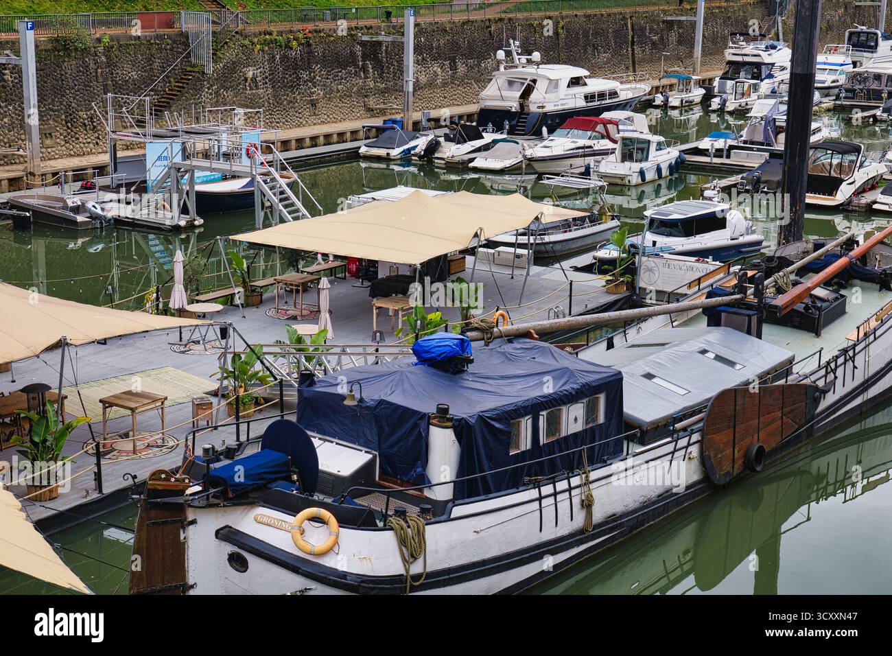 Marina Bar flottant avec des tables de parapluies et des Houseboats amarrés dans l'eau calme sous ciel couvert à Düsseldorf Allemagne Banque D'Images
