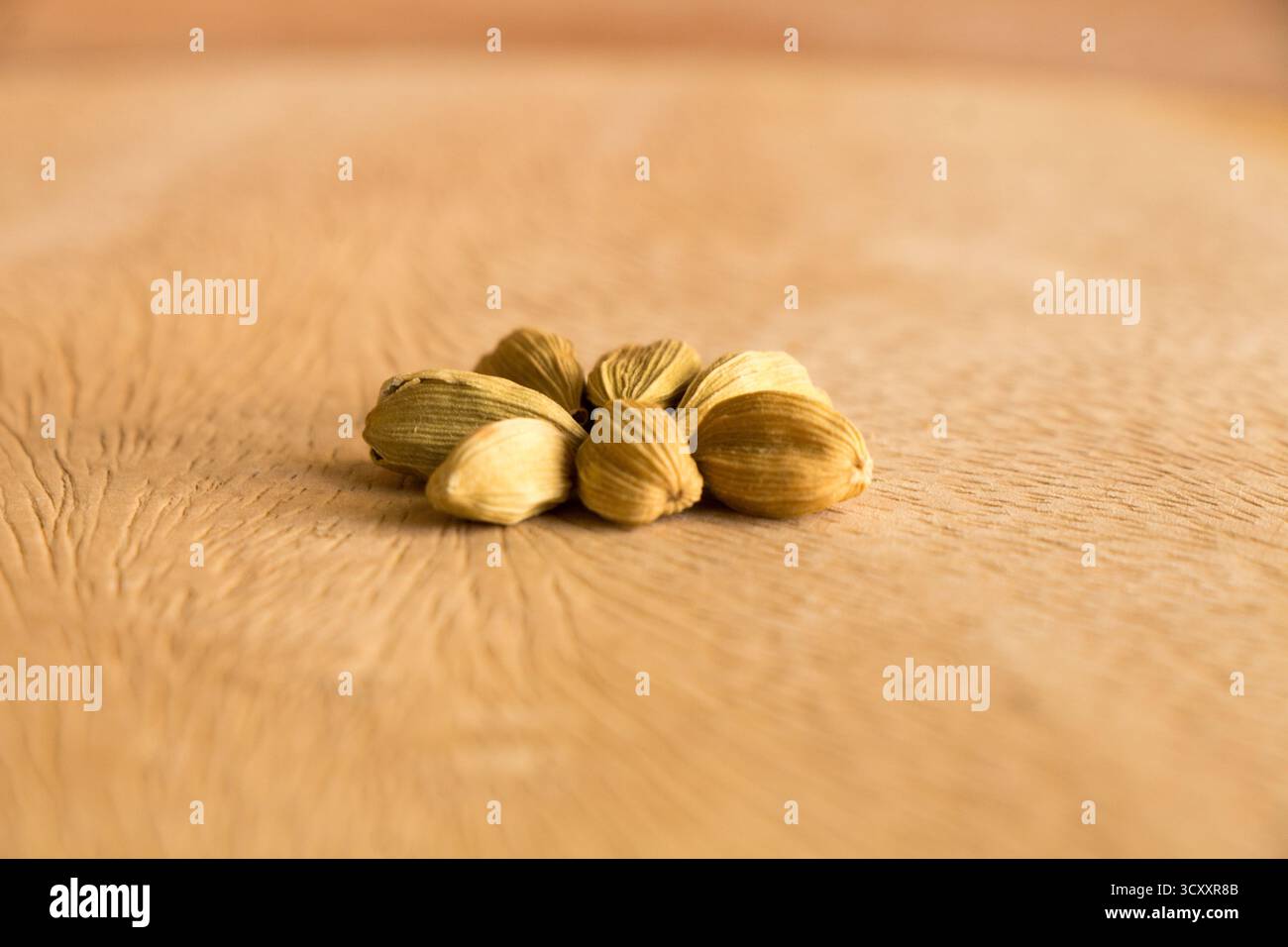 Un tas de gousses de cardamome présentées dans une composition de nature morte sur une surface en bois rustique. Gros plan sur cette épice aromatique. Banque D'Images Un tas de gousses de cardamome présentées dans une composition de nature morte sur une surface en bois rustique. Gros plan sur cette épice aromatique. Banque D'Images