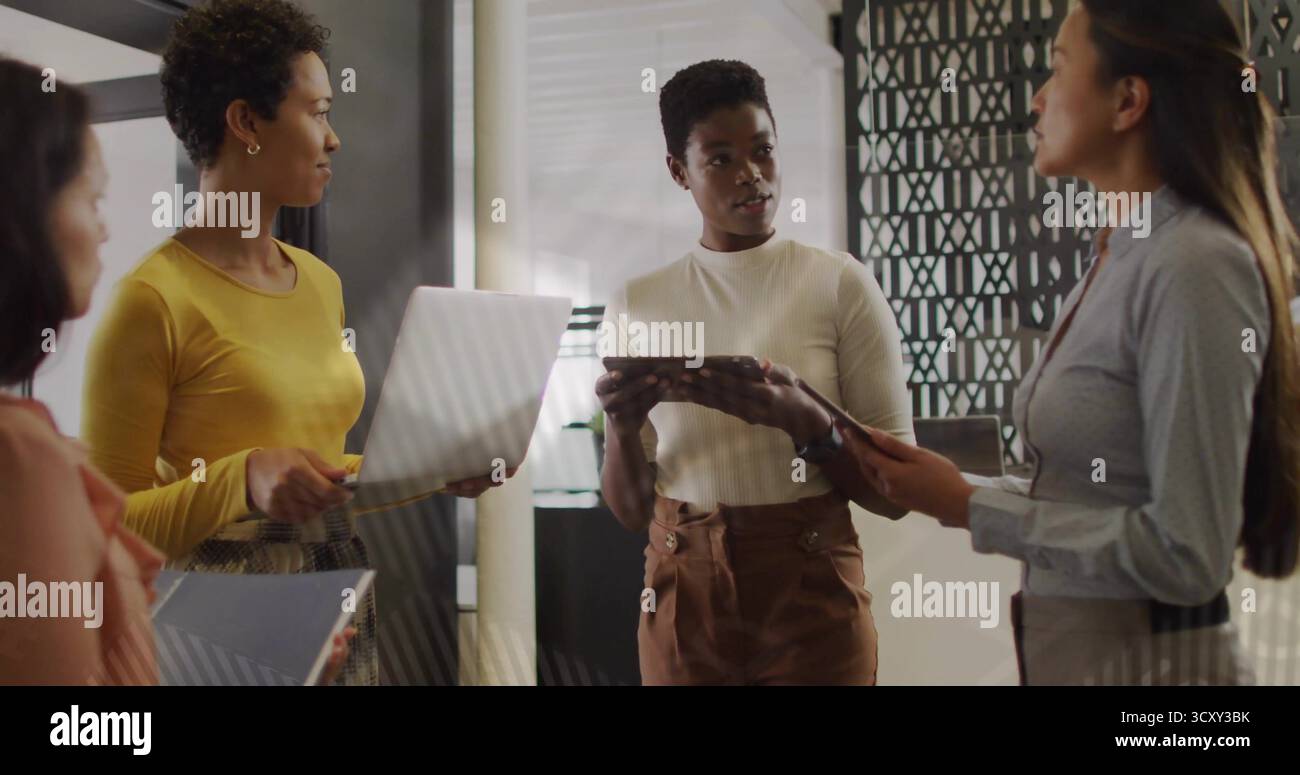 Collaboration des femmes dans des vêtements d'affaires décontractés à l'aide d'ordinateurs portables et d'appareils mobiles dans l'espace de travail de bureau Banque D'Images