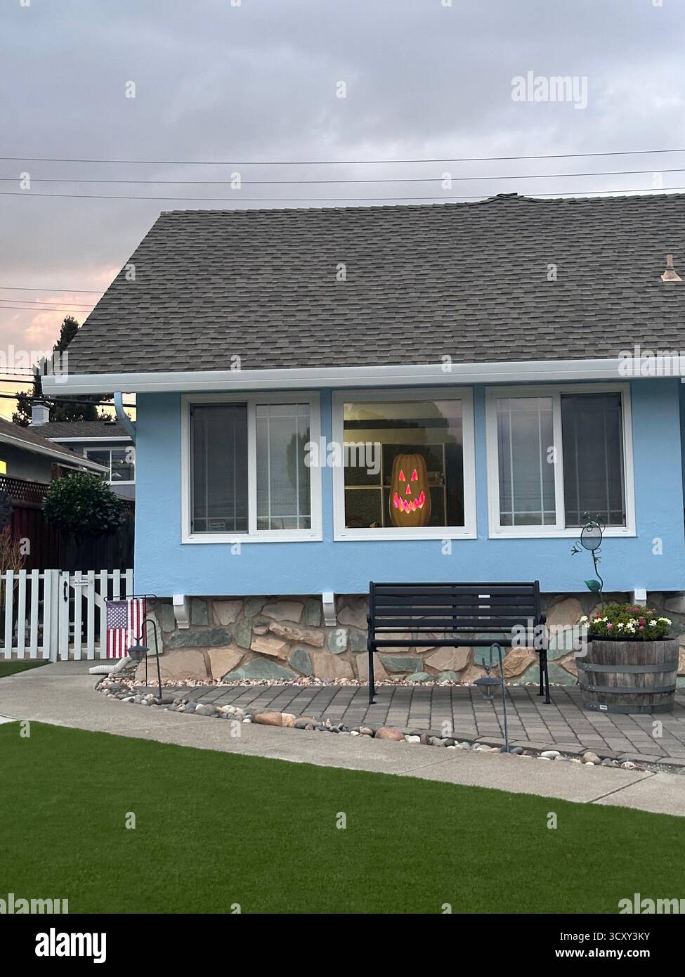 Visage de citrouille éclatant dans la fenêtre de banlieue – scène d'Halloween en Californie - Image de stock capturée avec un smartphone