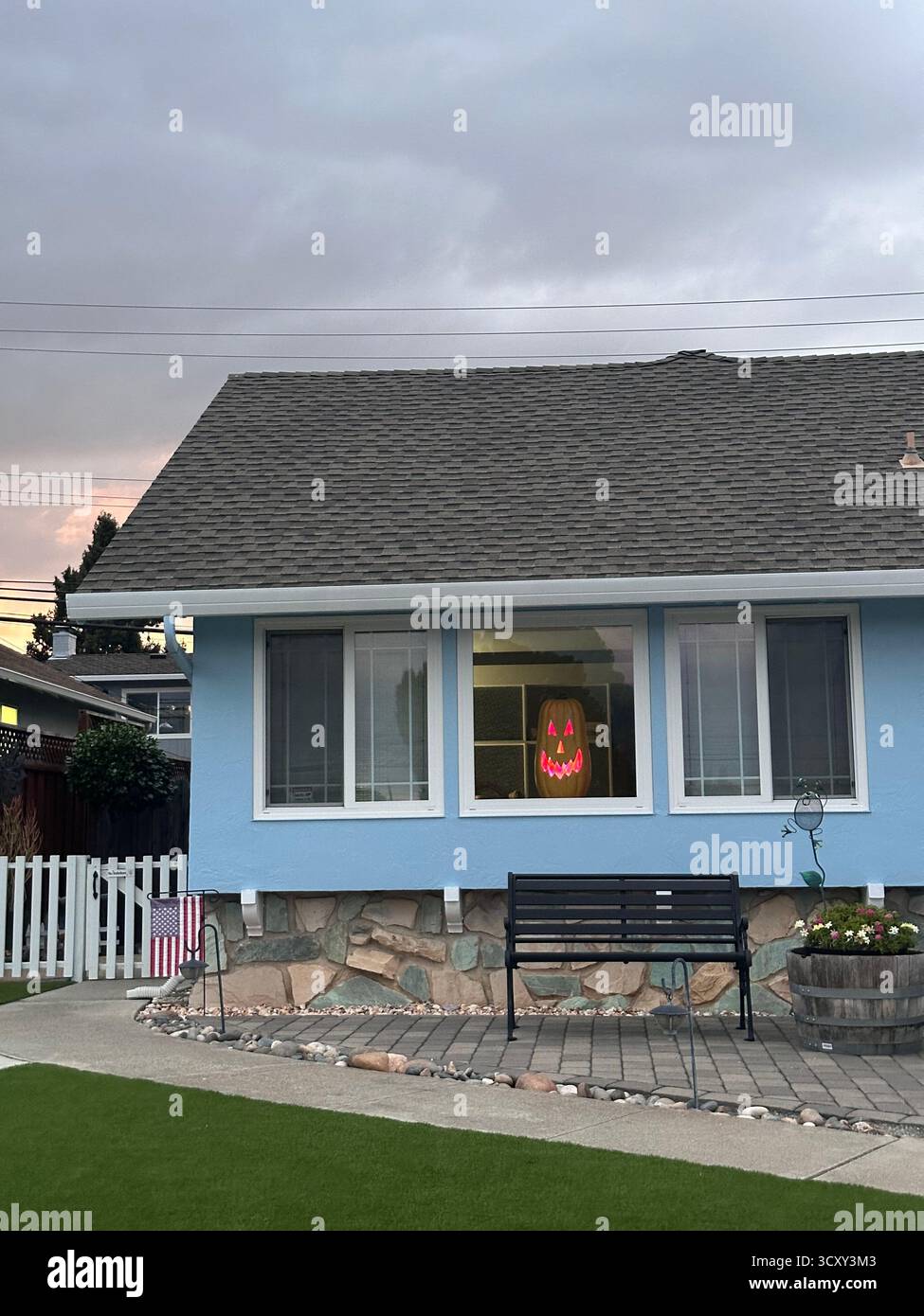 Visage de citrouille éclatant dans la fenêtre de banlieue – scène d'Halloween en Californie Banque D'Images