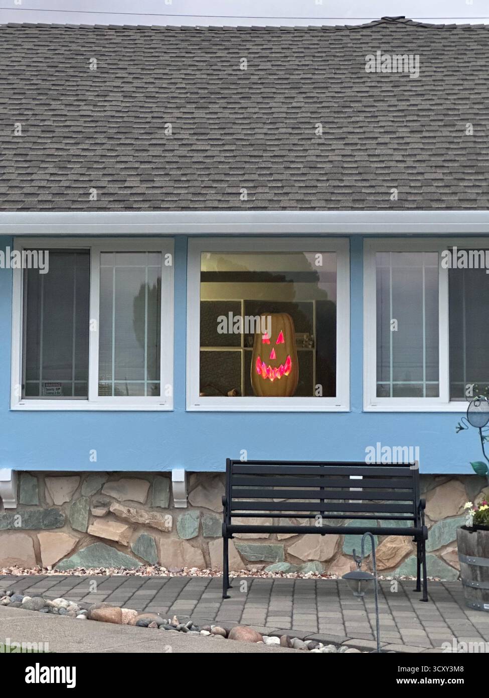 Visage de citrouille éclatant dans la fenêtre de banlieue – scène d'Halloween en Californie - Image de stock capturée avec un smartphone