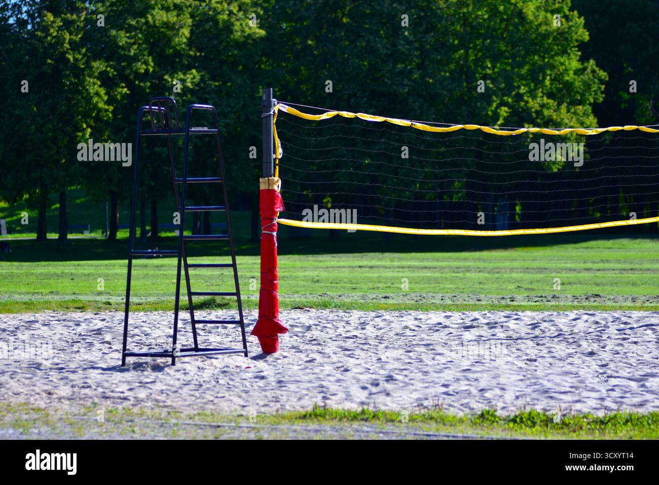 Terrain de volley-ball extérieur avec filet et échelle d'arbitre sur terrain sablonneux. Environnement paisible du parc par une journée ensoleillée parfait pour le sport et les loisirs. Banque D'Images