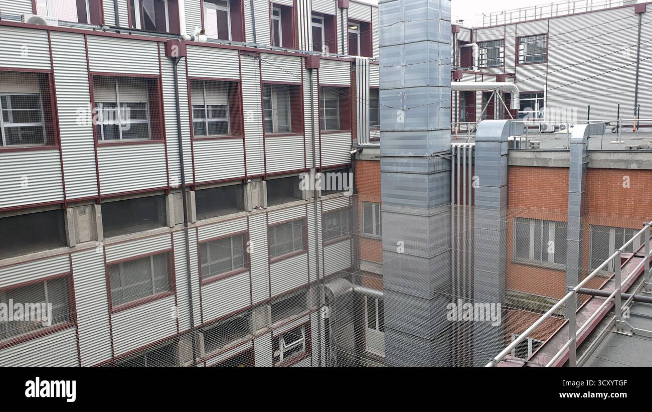 Cour extérieure d'un hôpital moderne montrant les installations techniques, les canalisations et les fenêtres de la chambre des patients. Parfait pour illustrer la maintenance, sa Banque D'Images