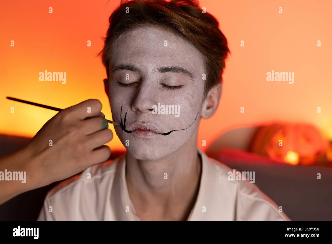 Quelqu'un applique le maquillage sur le thème d'Halloween sur le visage d'une personne Banque D'Images