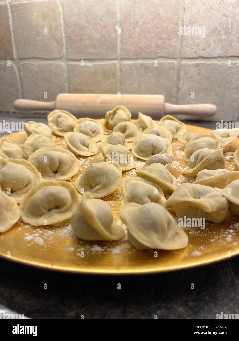 Boulettes maison non cuites sur la plaque dorée dans la cuisine et un rouleau à pâtisserie. - Image de stock capturée avec un smartphone