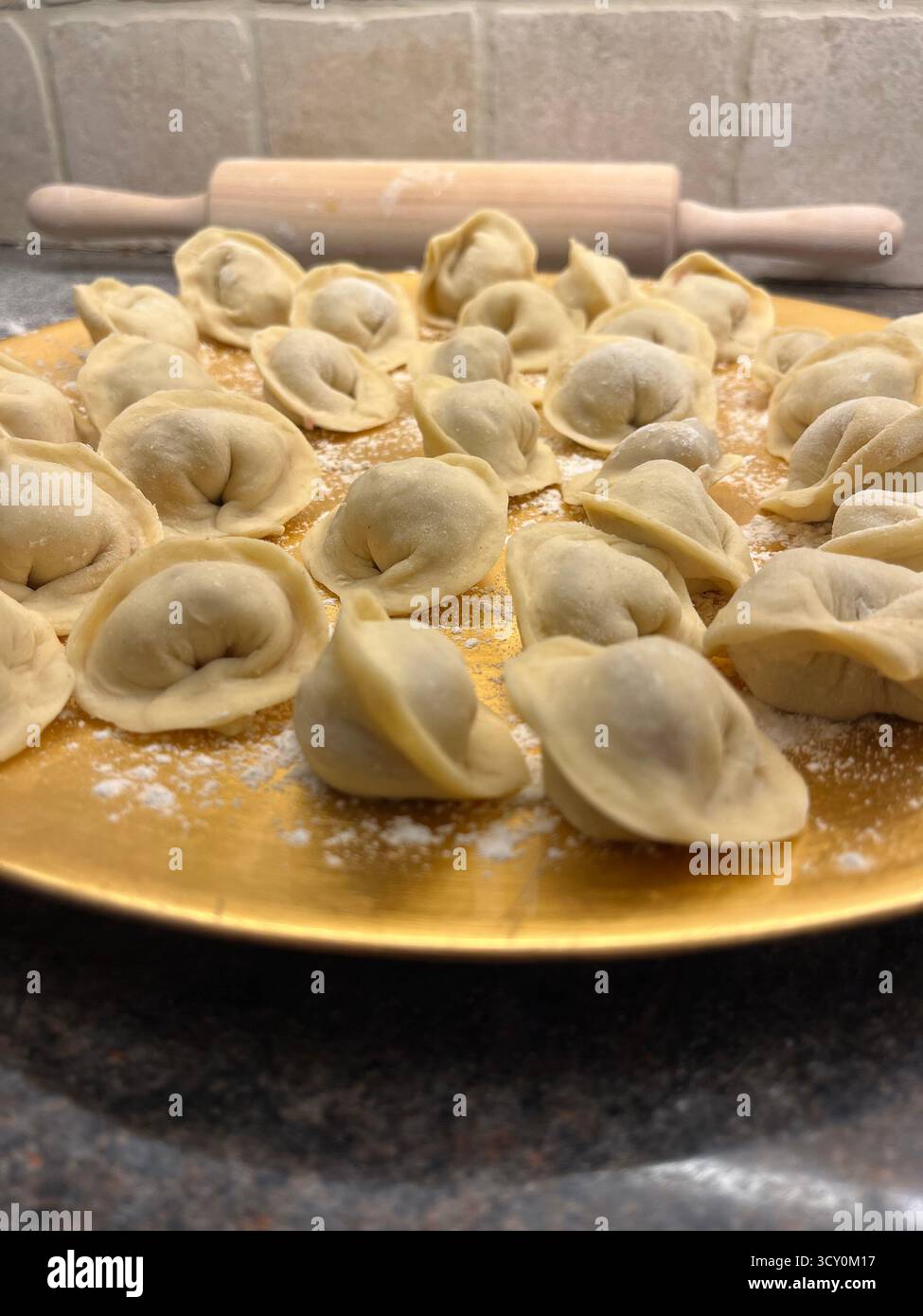 Boulettes maison non cuites sur la plaque dorée dans la cuisine et un rouleau à pâtisserie. - Image de stock capturée avec un smartphone