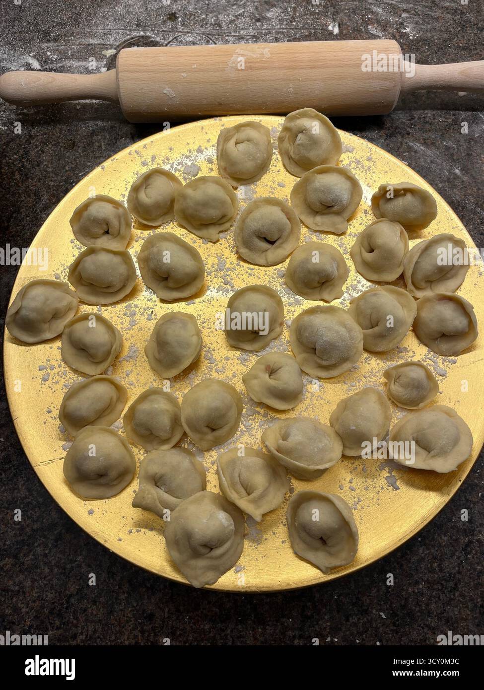 Boulettes maison non cuites sur la plaque dorée dans la cuisine et un rouleau à pâtisserie. - Image de stock capturée avec un smartphone