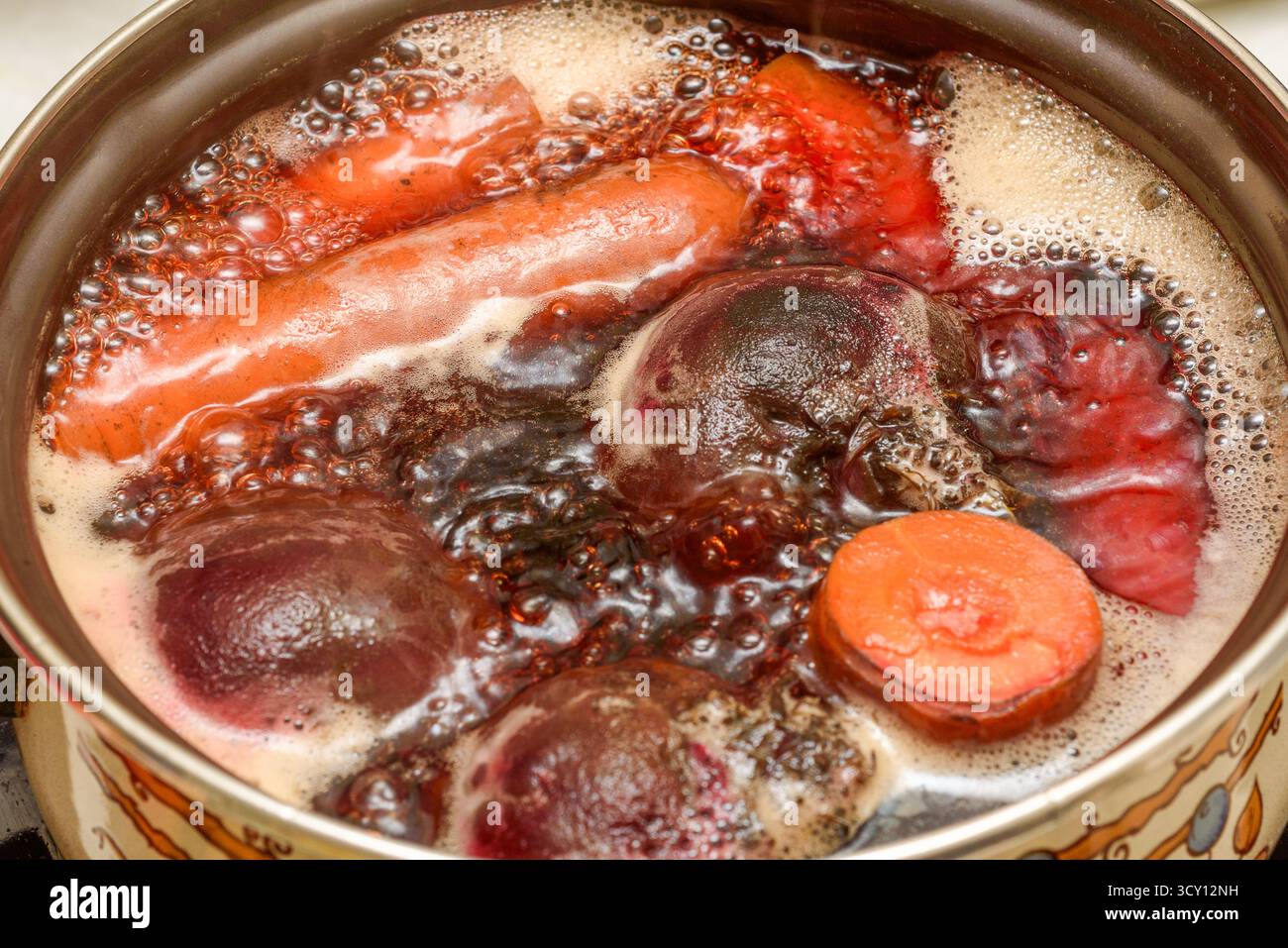 Les carottes et les betteraves fraîches sont bouillies dans une casserole d'eau. Préparation de légumes pour les salades. Cuisine domestique. Banque D'Images