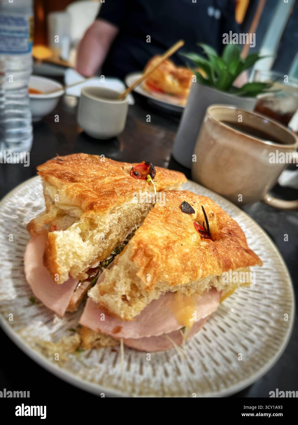 Délicieux sandwich au jambon et au fromage sur un croissant servi avec une tasse de café dans un cadre de café confortable. - Image de stock capturée avec un smartphone
