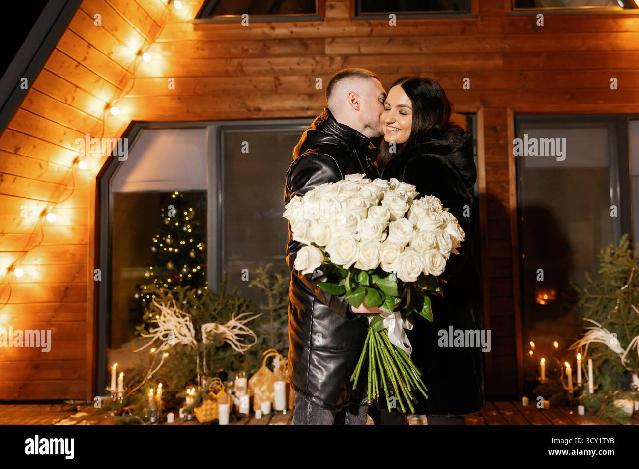 Couple romantique célébrant l'anniversaire ou la Saint-Valentin avec un énorme bouquet de roses blanches Banque D'Images