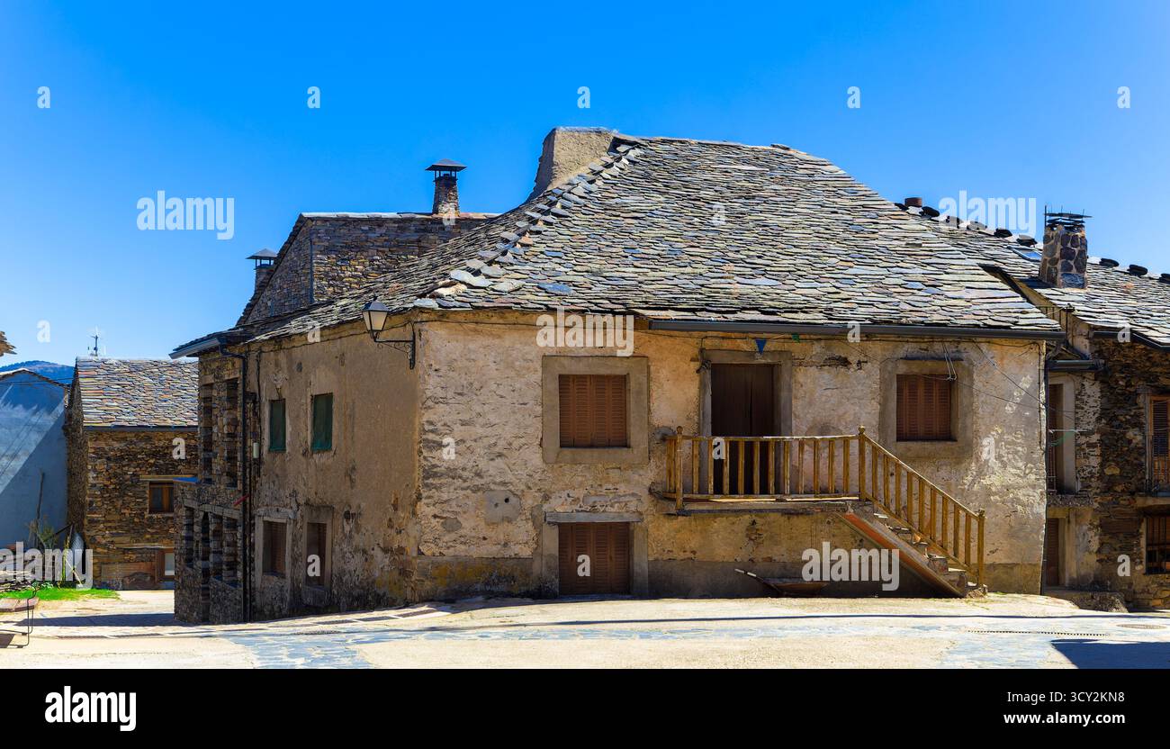 Une vieille maison dans un village médiéval avec un toit en ardoise et des escaliers en bois menant à l'entrée principale. Le bâtiment montre des signes de dommages et semble Banque D'Images