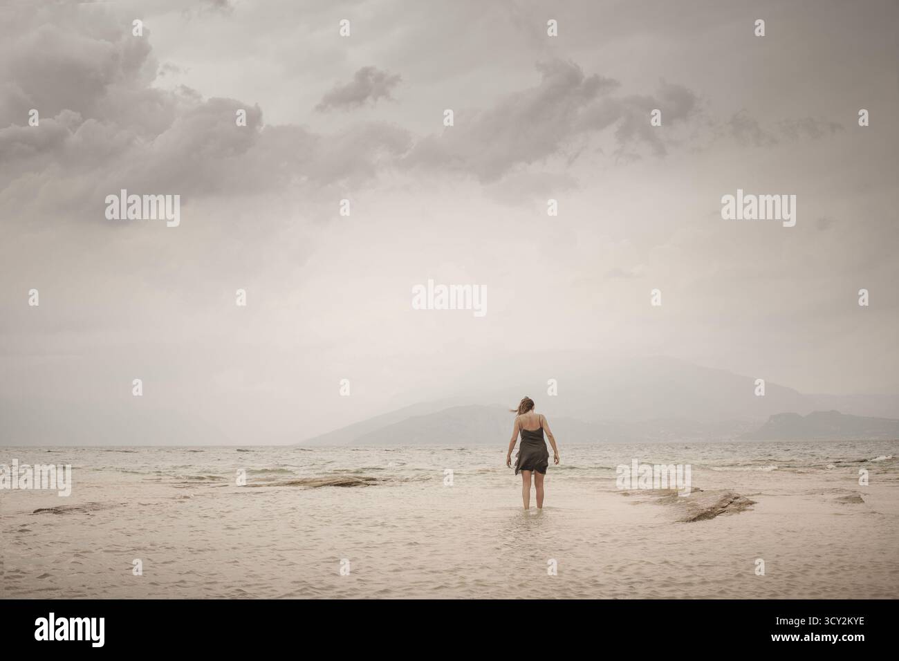 Une femme dans le vent marchant vers l'infini au-delà du bord de la mer Banque D'Images