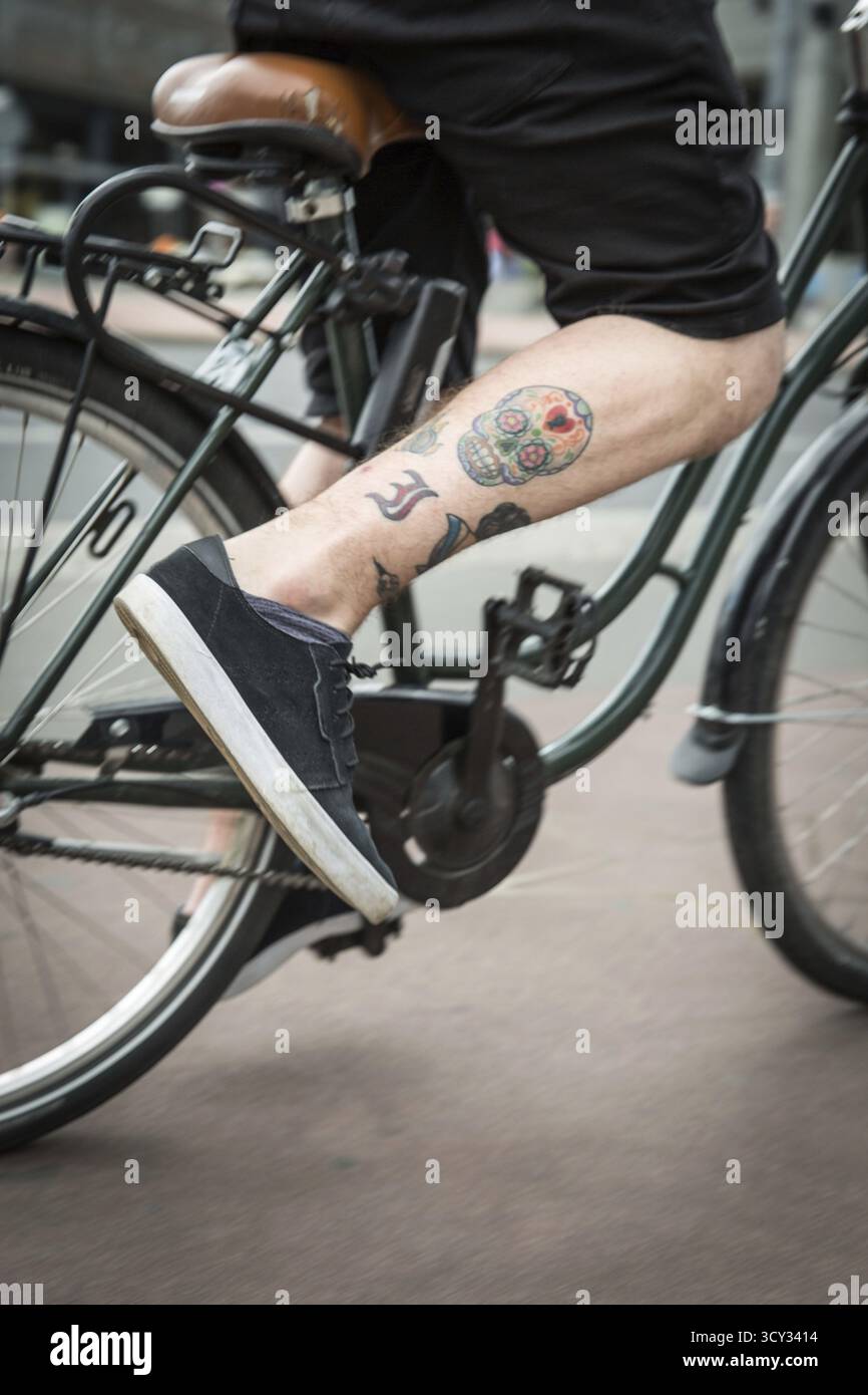 DEU Allemagne Berlin Un tatouage crâne sur la jambe d'un cycliste Banque D'Images