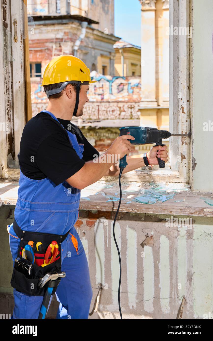 Travailleur rénovant le bâtiment avec outil électrique dans le site historique Banque D'Images