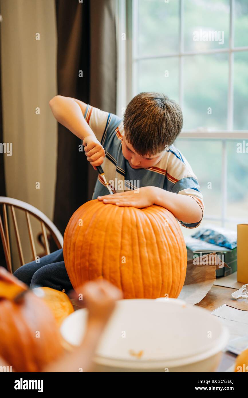 Garçon sculptant la citrouille pour halloween pendant le plaisir de l'automne Banque D'Images