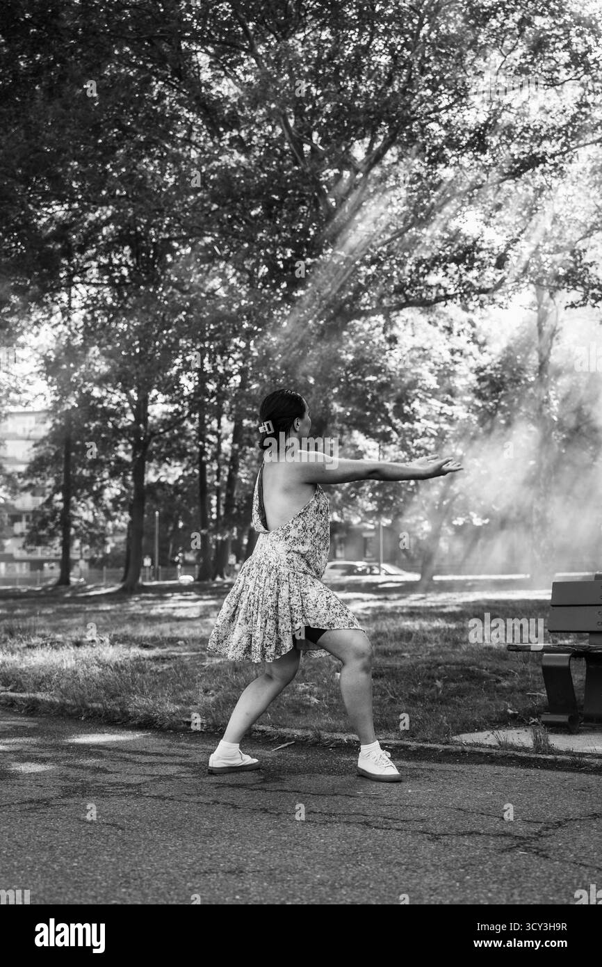 Femme étend les bras dans une position dramatique sous les rayons de lumière de la forêt Banque D'Images