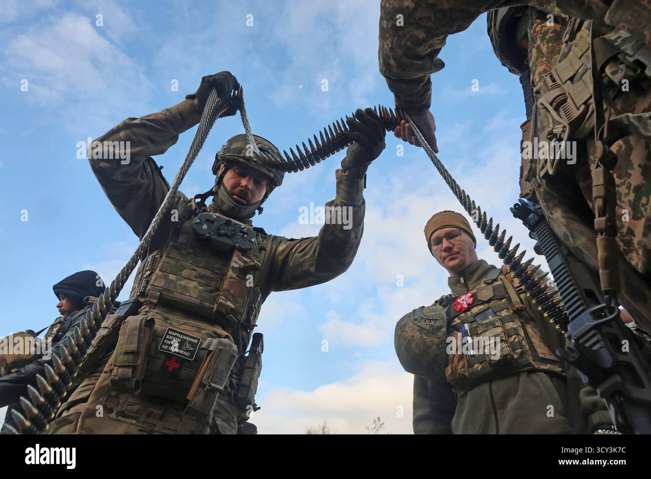 Des soldats de la 13ème Brigade de Khartiia de la Garde nationale ukrainienne tiennent une ceinture de mitrailleuses lors d’un exercice de tir avec des armes fabriquées en Ukraine et à l’étranger dans la région de Kharkiv, Ukraine, le 13 octobre 2025. (Photo de Viacheslav Madiievskyi/Ukrinform) Banque D'Images