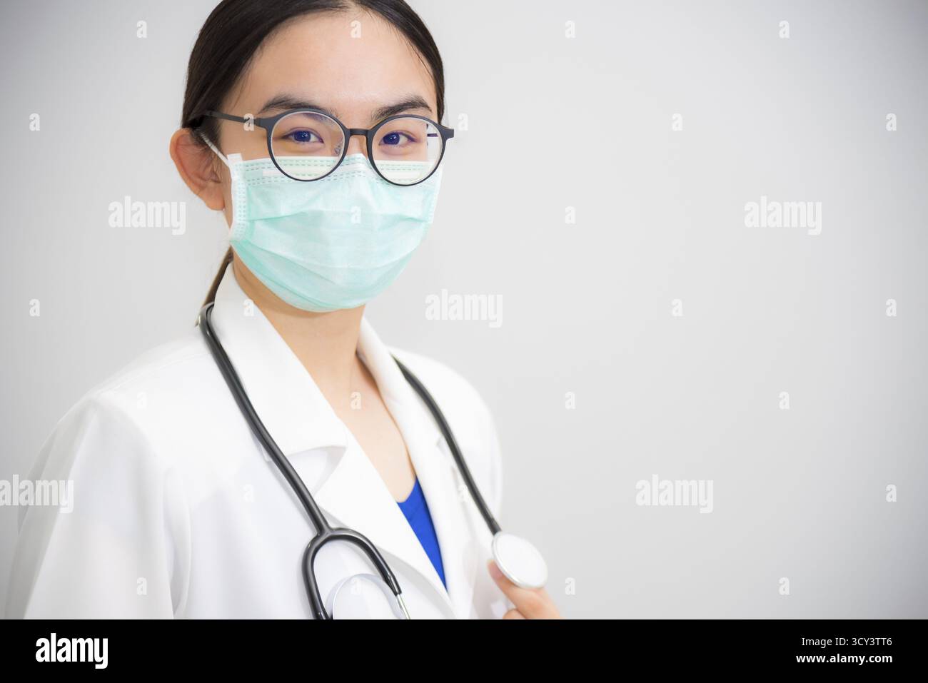 Studio portrait beau médecin de jeune femme asiatique avec stéthoscope en lunettes de soleil uniformes blanches et masque vert pour protéger Corona virus for Health lo Banque D'Images