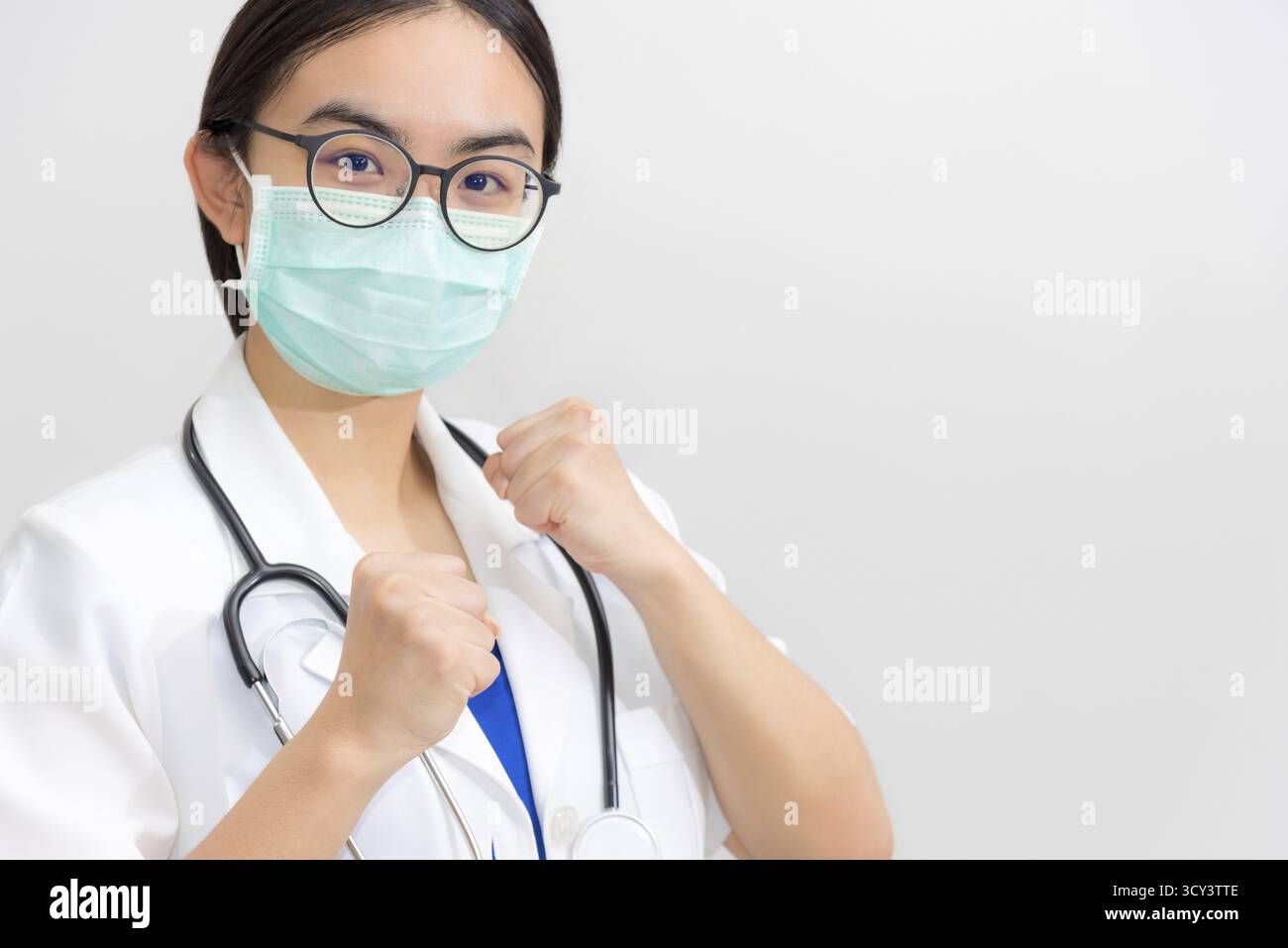 Belle jeune femme asiatique médecin en uniforme blanc et masque protéger le coronavirus, le médecin lève les poings pour soutenir le patient dans la lutte contre les diseas Banque D'Images