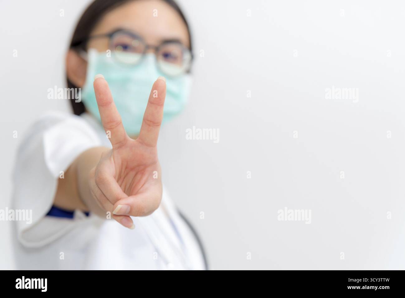 Studio portrait Asian jeune femme médecin closeup lever deux V forme doigt porter un masque à la sécurité Coronavirus pour soutenir dans la lutte contre la maladie ep Banque D'Images