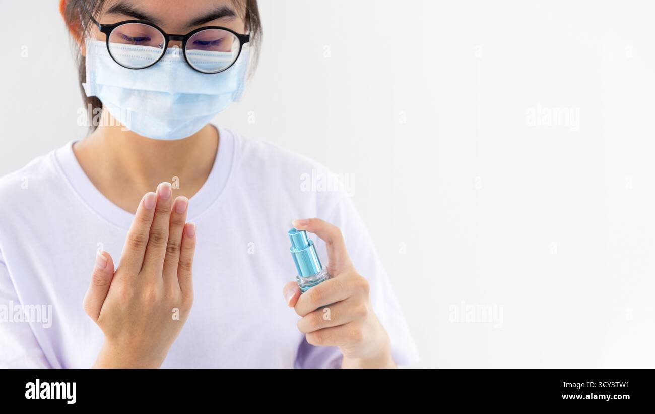 La jeune femme asiatique porte un masque pour protéger le nettoyage des mains avec de l'alcool pulvérisé arrêter l'éclosion de coronavirus ou empêcher la propagation du virus Covid 19 isola Banque D'Images