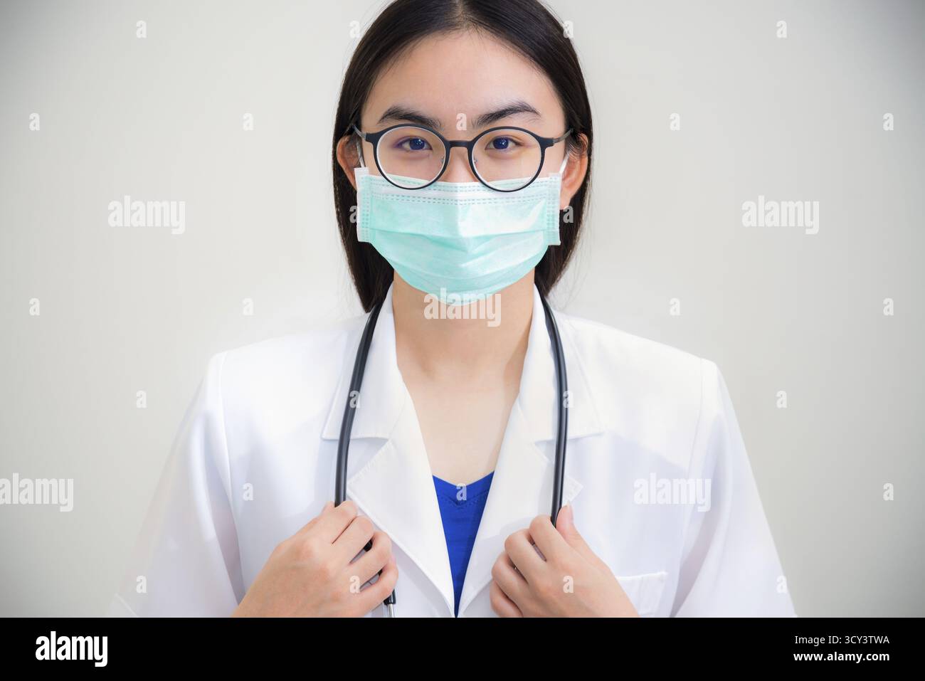 Studio portrait face avant belle jeune femme asiatique médecin avec stéthoscope en lunettes de soleil uniformes blanches et masque vert pour protéger Corona virus FO Banque D'Images