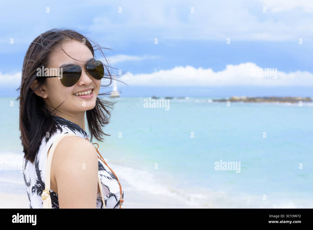 Belle femme port touristique sunglasse regardant la caméra et souriant de plaisir sur la plage et la mer en fond de ciel d'été à Koh Tarutao est Banque D'Images