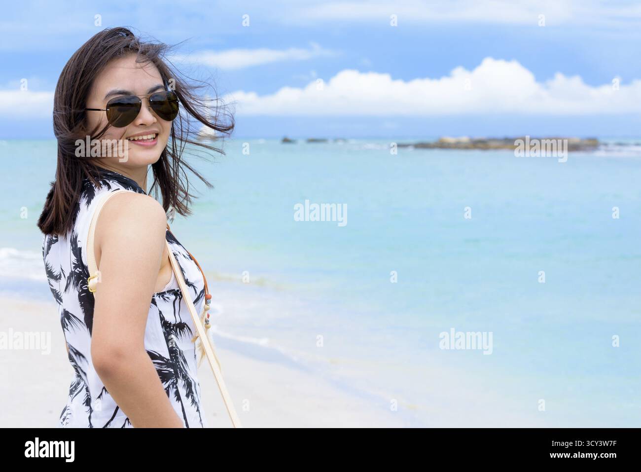 Belle femme port touristique sunglasse regardant la caméra et souriant de plaisir sur la plage et la mer en fond de ciel d'été à Koh Tarutao est Banque D'Images