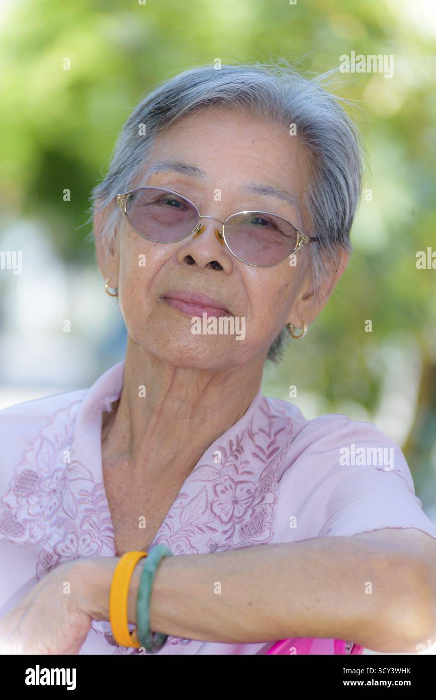 La tête a tourné près de la face avant d'une belle femme en bonne santé des personnes asiatiques âgées habillent dans des vêtements de style thaïlandais, Portrait vieille dame se relaxant à l'extérieur dans le Banque D'Images