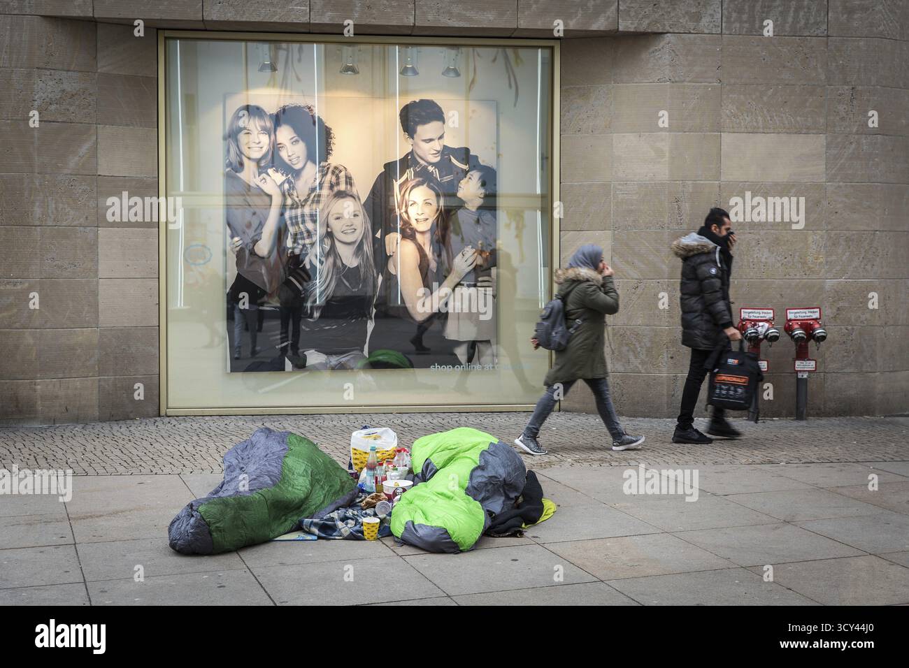 DEU Allemagne Berlin deux sans-abri gisent devant une publicité de grand magasin sur Alexanderplatz. Deux passants tiennent leur nez comme ils le veulent Banque D'Images