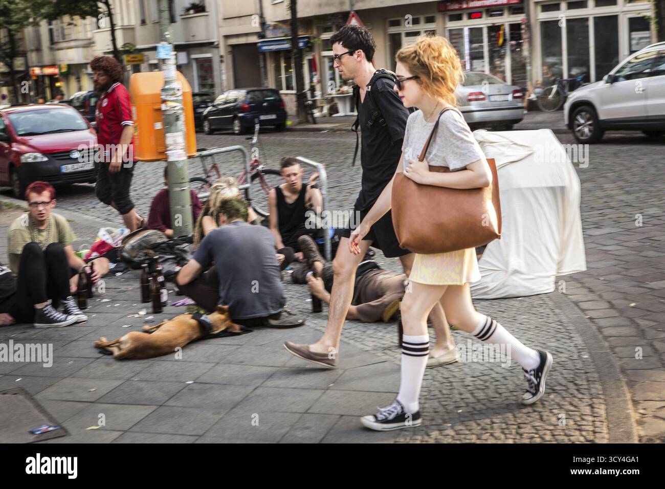 DEU Allemagne Berlin scène du quartier des collectionneurs de Berlin-Friedrichshain. Homme et femme passent des punks polonais assis devant un 'Ka Banque D'Images