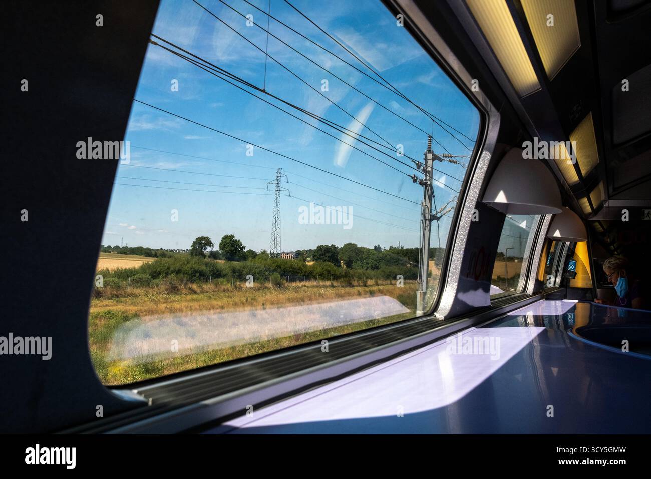 Vue depuis une fenêtre de train montrant la campagne avec des champs et des pylônes électriques sous un ciel bleu départ de Rennes en Ille et Vilaine en Bretagne i. Banque D'Images