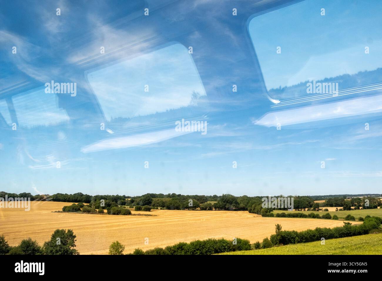 Vue d'une fenêtre de train montrant la campagne avec champ d'agriculture sous un ciel bleu départ de Rennes en Ille et Vilaine en Bretagne en France Banque D'Images