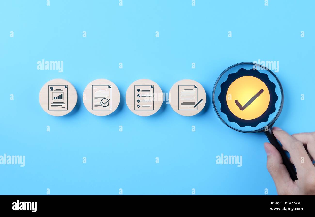Concept de contrôle qualité et d'assurance de certification. Main tenant la loupe au-dessus du symbole de coche, à côté des icônes représentant le contrôle qualité Banque D'Images