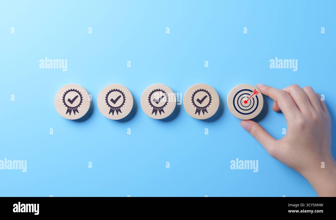 Concept standard de contrôle qualité et de certification. La main place le bloc en bois avec l'icône cible parmi les blocs avec des coches, contrôle de qualité standard, Banque D'Images