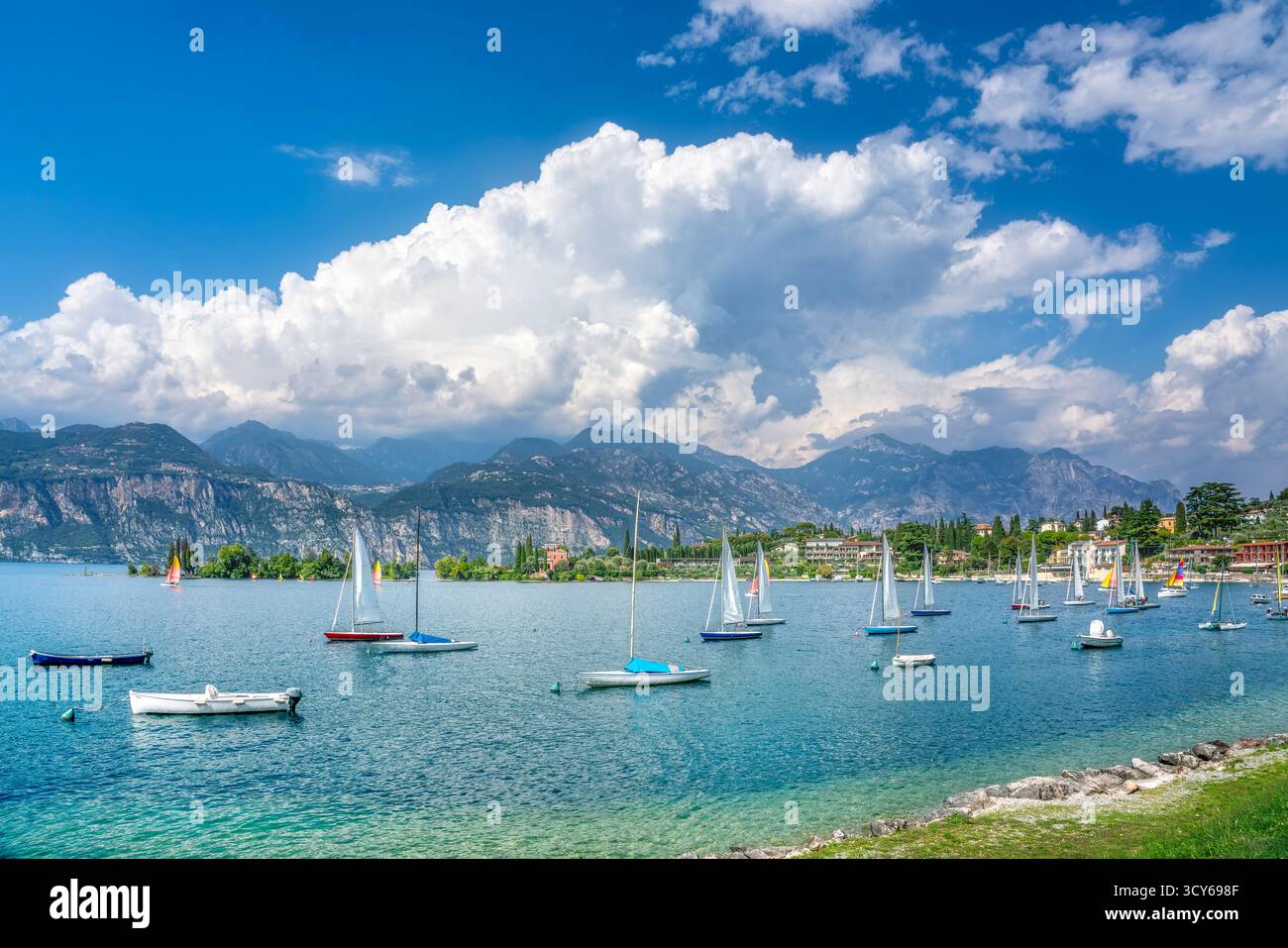Voiliers ancrés dans les eaux turquoises de la baie de Val di Sogno à Malcesine, lac de Garde. Montagnes spectaculaires et nuages blancs sur le lac alpin italien, Ven Banque D'Images